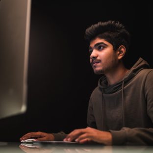 indian man hacker using computers for stealing data on desk